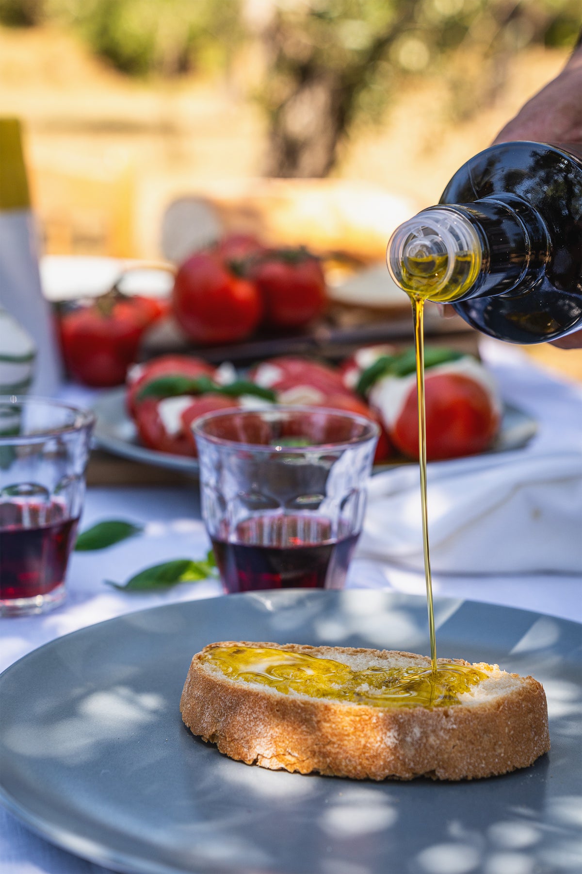 Olio extravergine versato su una fetta di pane tostato, su una tavola apparecchiata
